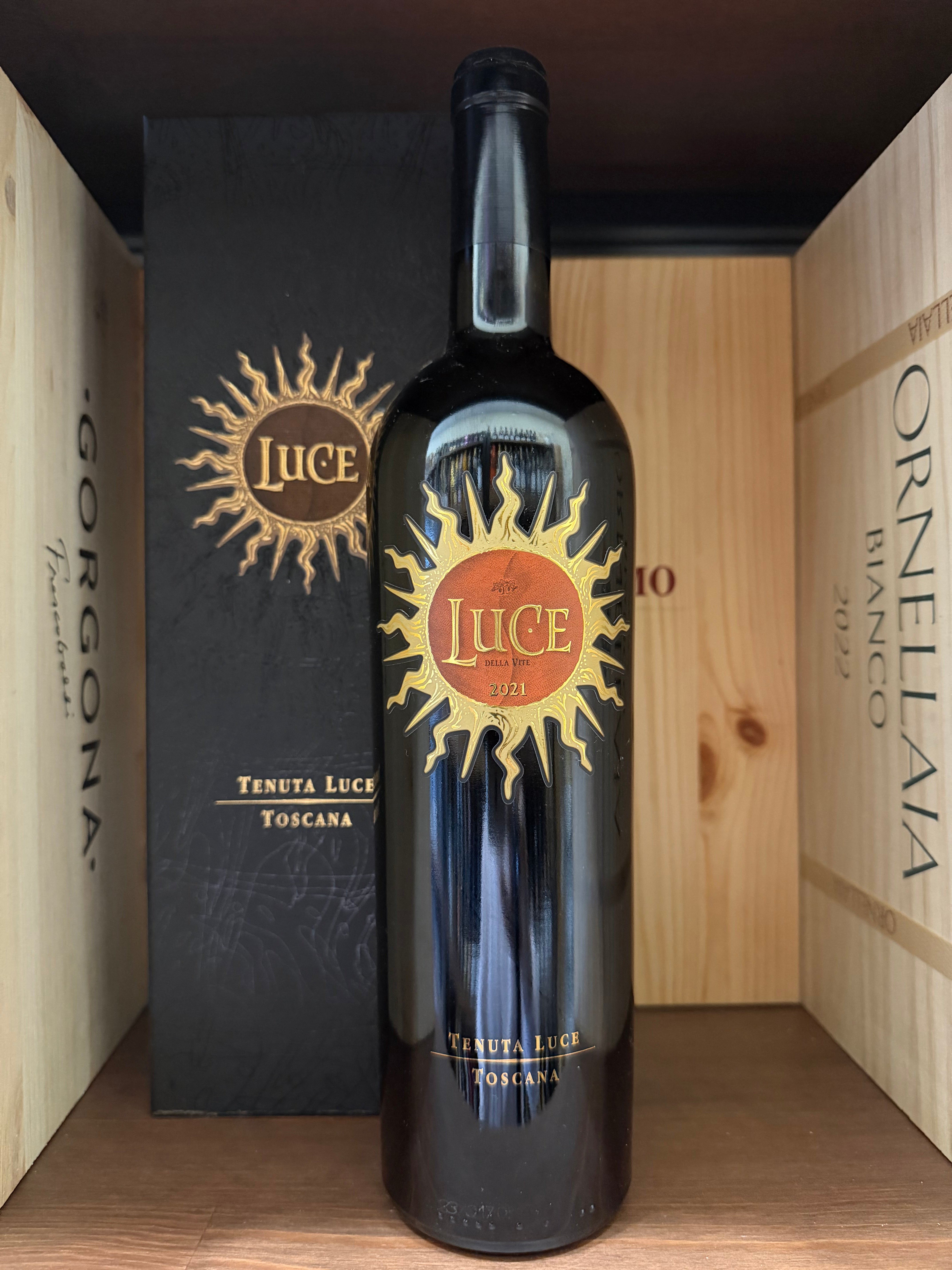 Bottiglia di vino rosso Luce 2021 Tenuta Luce, etichetta elegante, con calice di vino rosso e sfondo rustico.