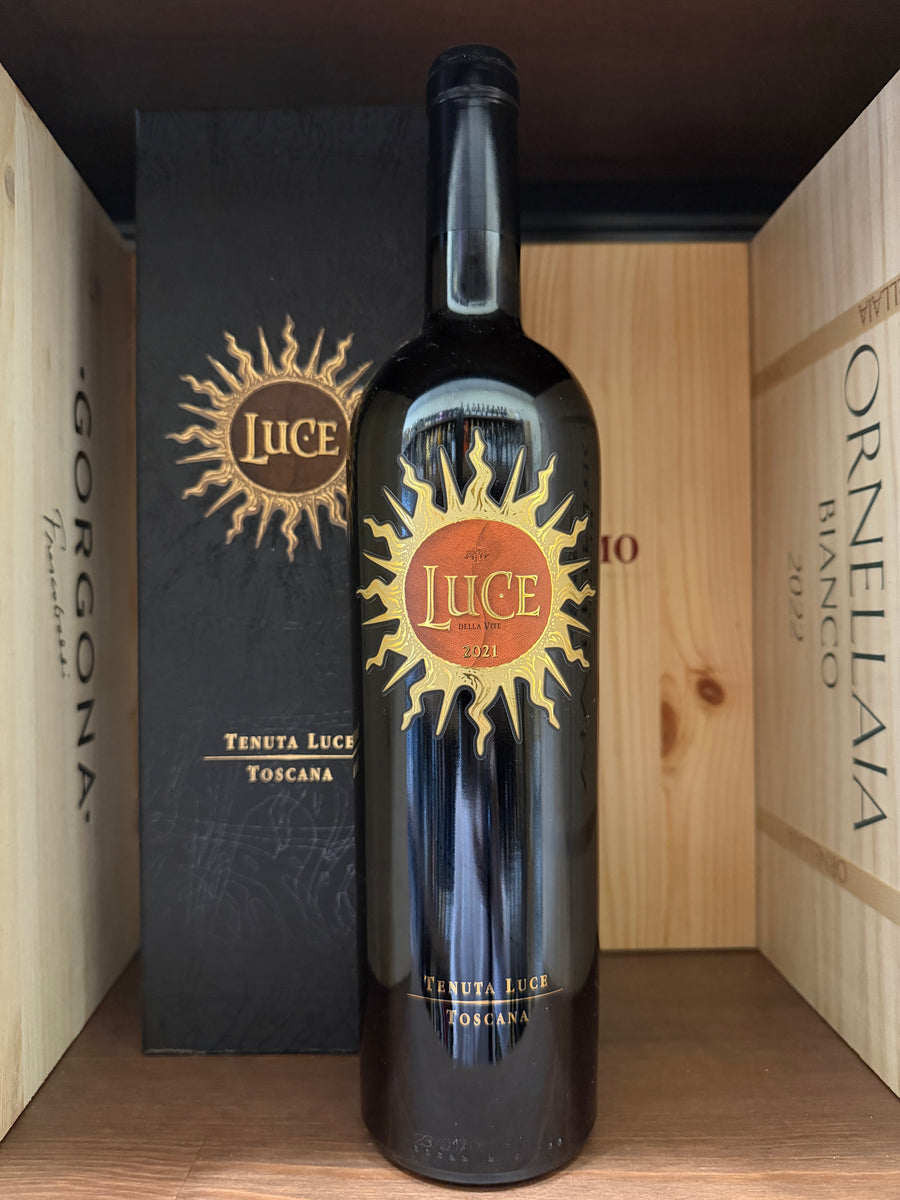 Bottiglia di vino rosso Luce 2021 Tenuta Luce, etichetta elegante, con calice di vino rosso e sfondo rustico.