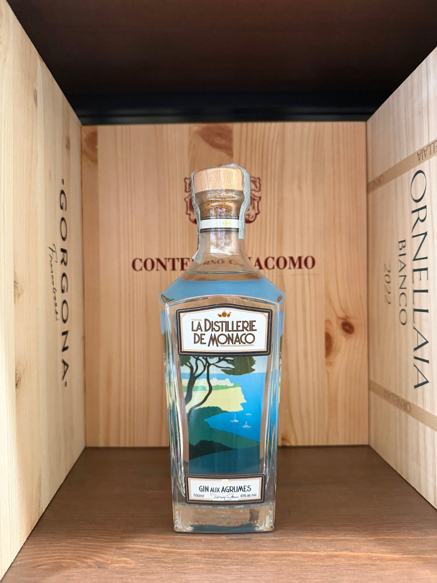 Bottiglia di gin Aux Agrumes di Distillerie de Monaco, con etichetta elegante, su sfondo neutro.