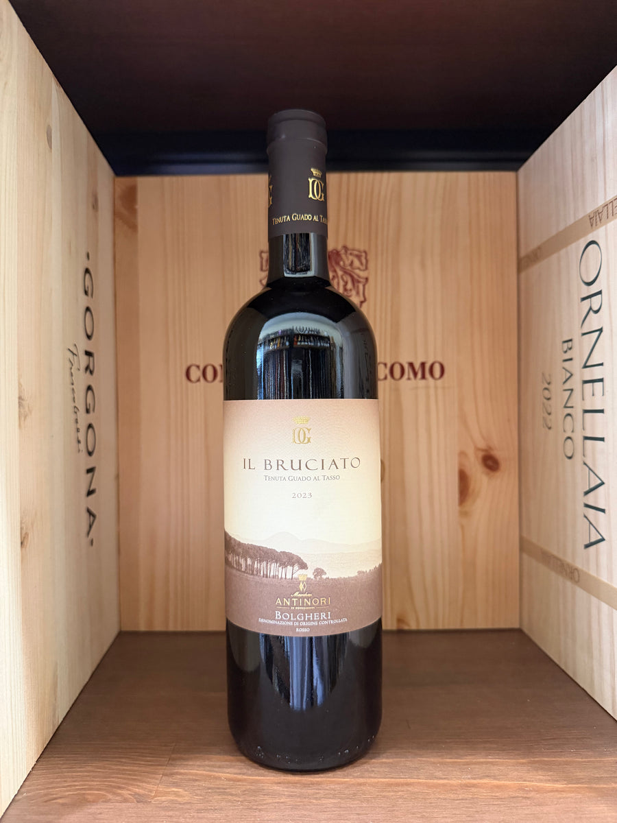 Bottiglia di vino Bolgheri 2023 Bruciato Tenuta Guado Al Tasso, con etichetta elegante, in un ambiente rustico e raffinato