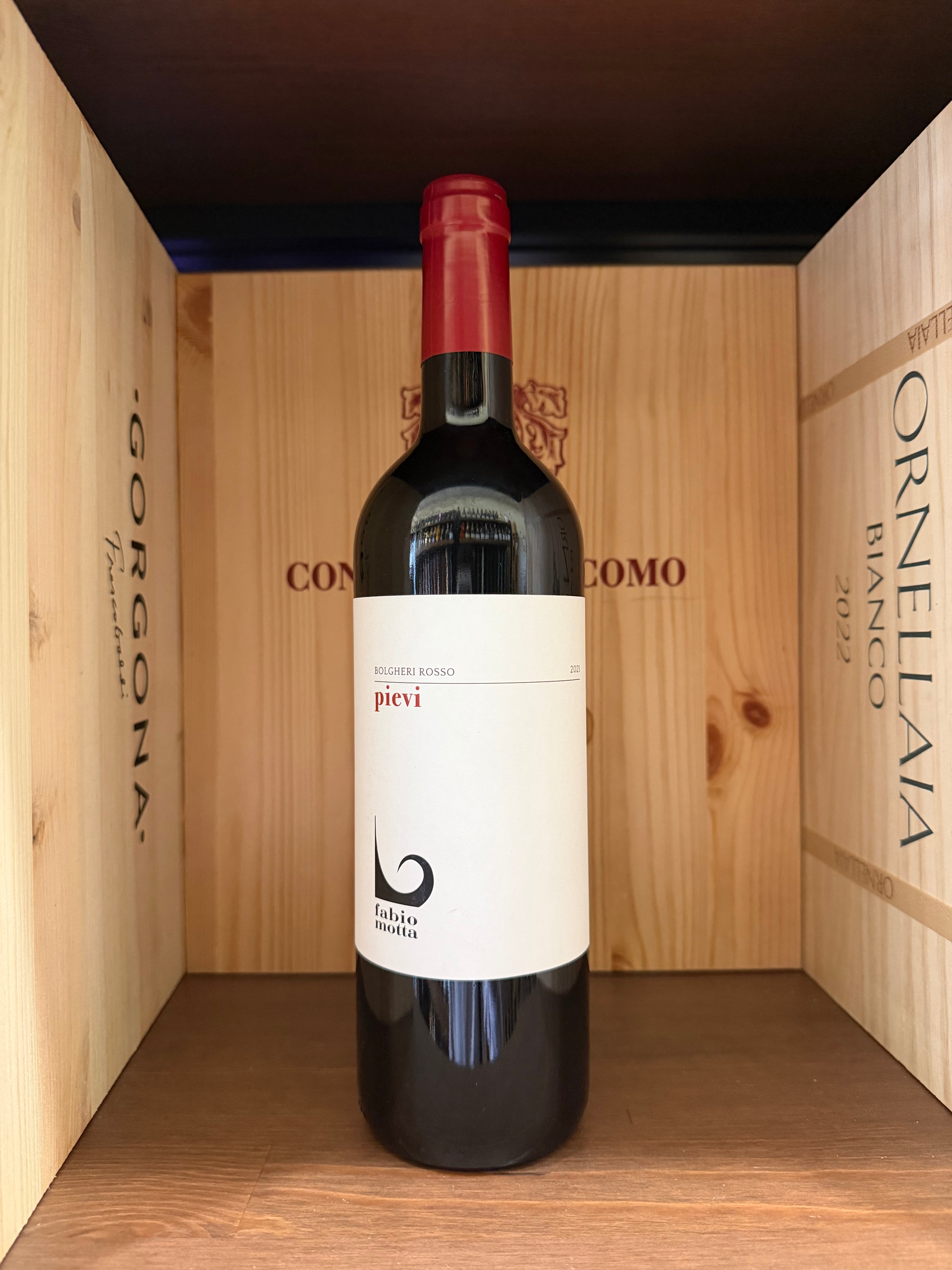 Bottiglia di vino rosso Pievi Bolgheri 2021 di Fabio Motta, etichetta elegante, in un calice di vino.