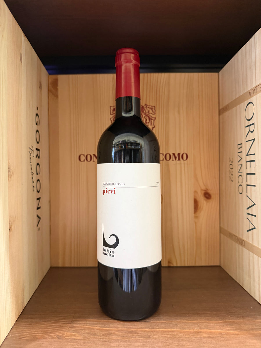 Bottiglia di vino rosso Pievi Bolgheri 2021 di Fabio Motta, etichetta elegante, in un calice di vino.