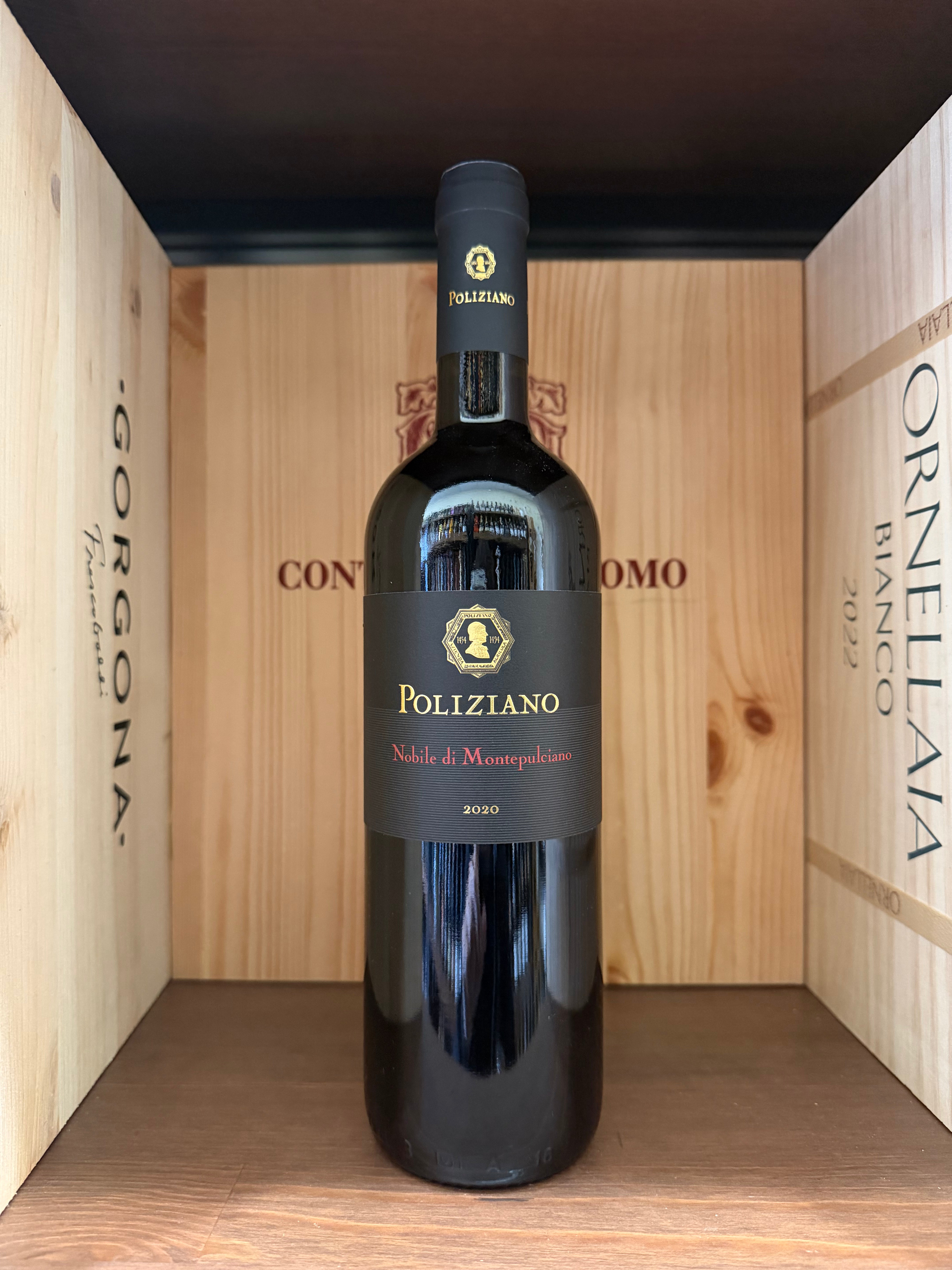 Bottiglia di vino Nobile di Montepulciano 2020 Poliziano, etichetta elegante, in una cantina con sfondo di bottiglie e bicchieri.