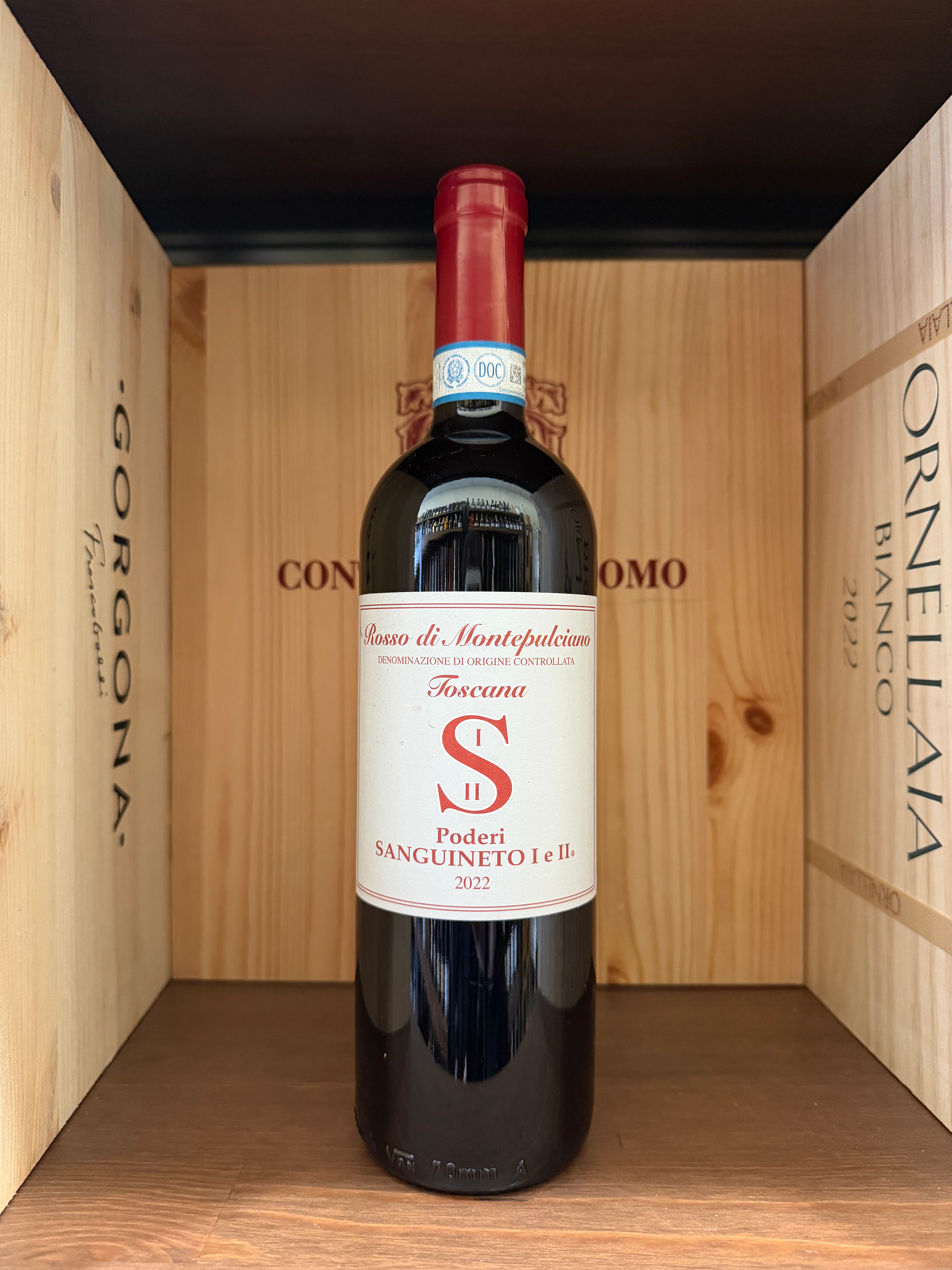 Bottiglia di vino Rosso di Montepulciano 2022 Podere Sanguineto con etichetta elegante, in un calice di vino rosso.