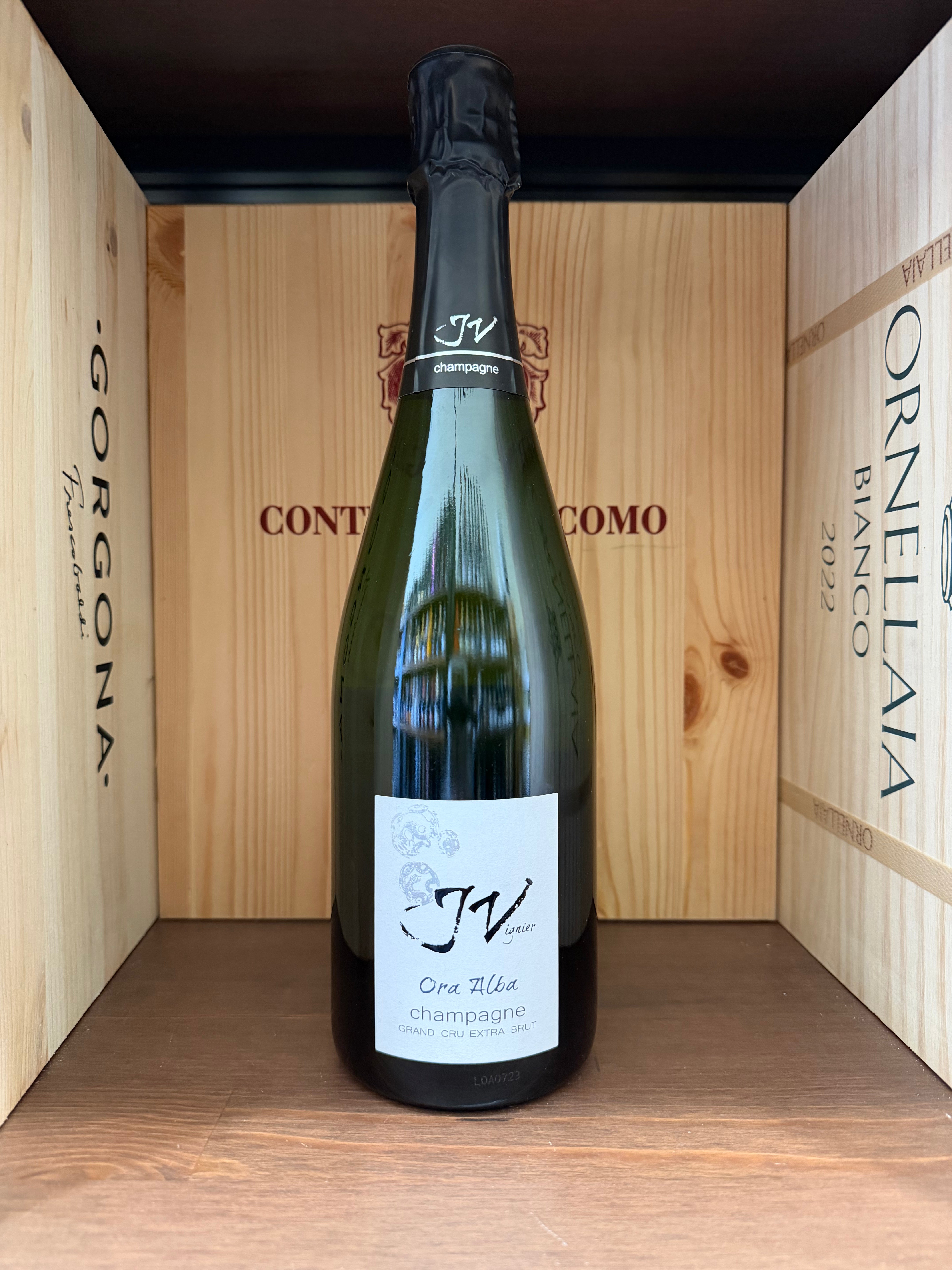 Bottiglia di vino J.Vignier Ora Alba Gran Cru Extra Brut, etichetta elegante, in un bicchiere da vino, su sfondo neutro.