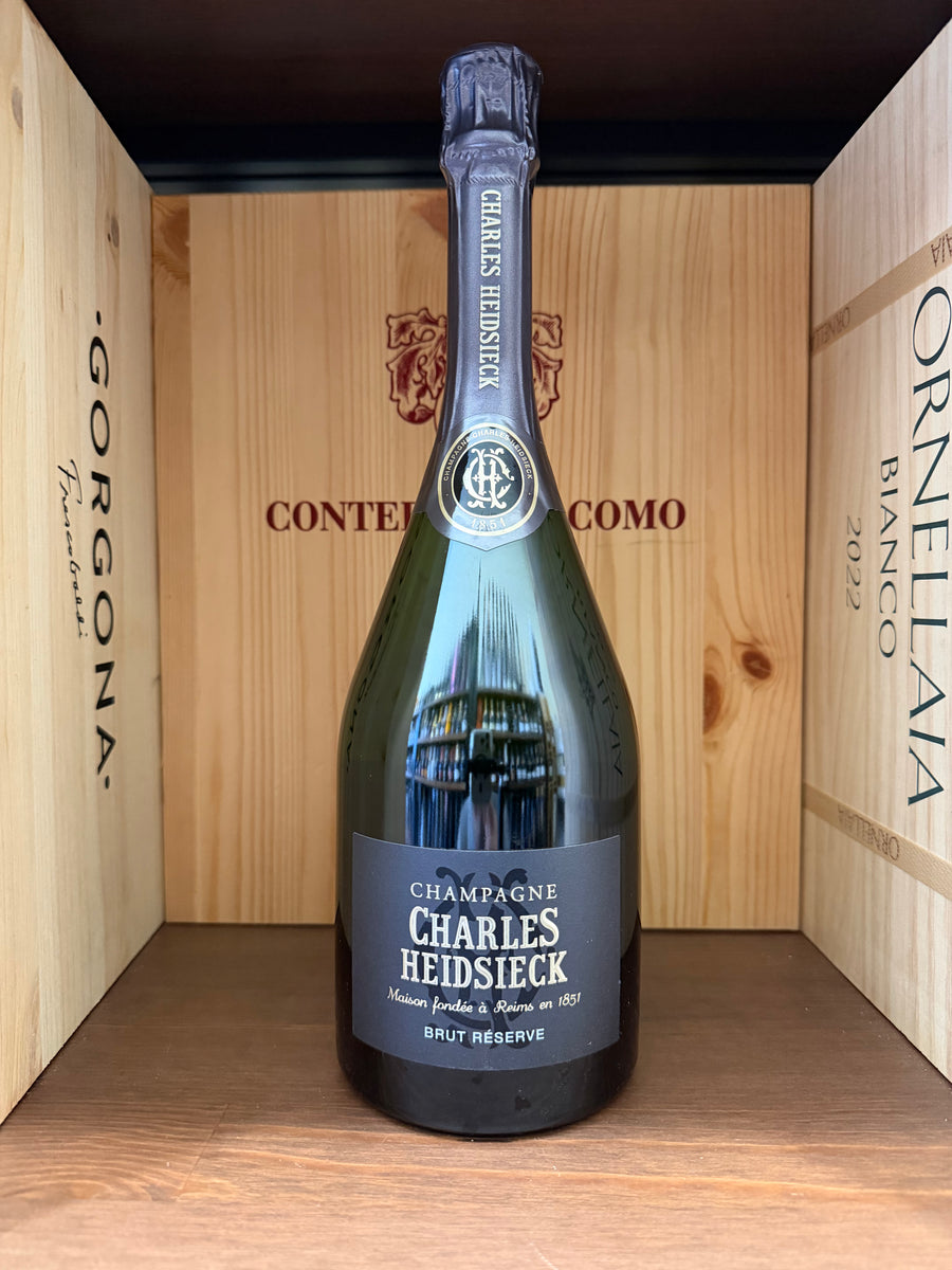 Flûte di champagne Charles Heidsieck Brut Réserve in un bicchiere, con etichetta visibile, su tavolo elegante.