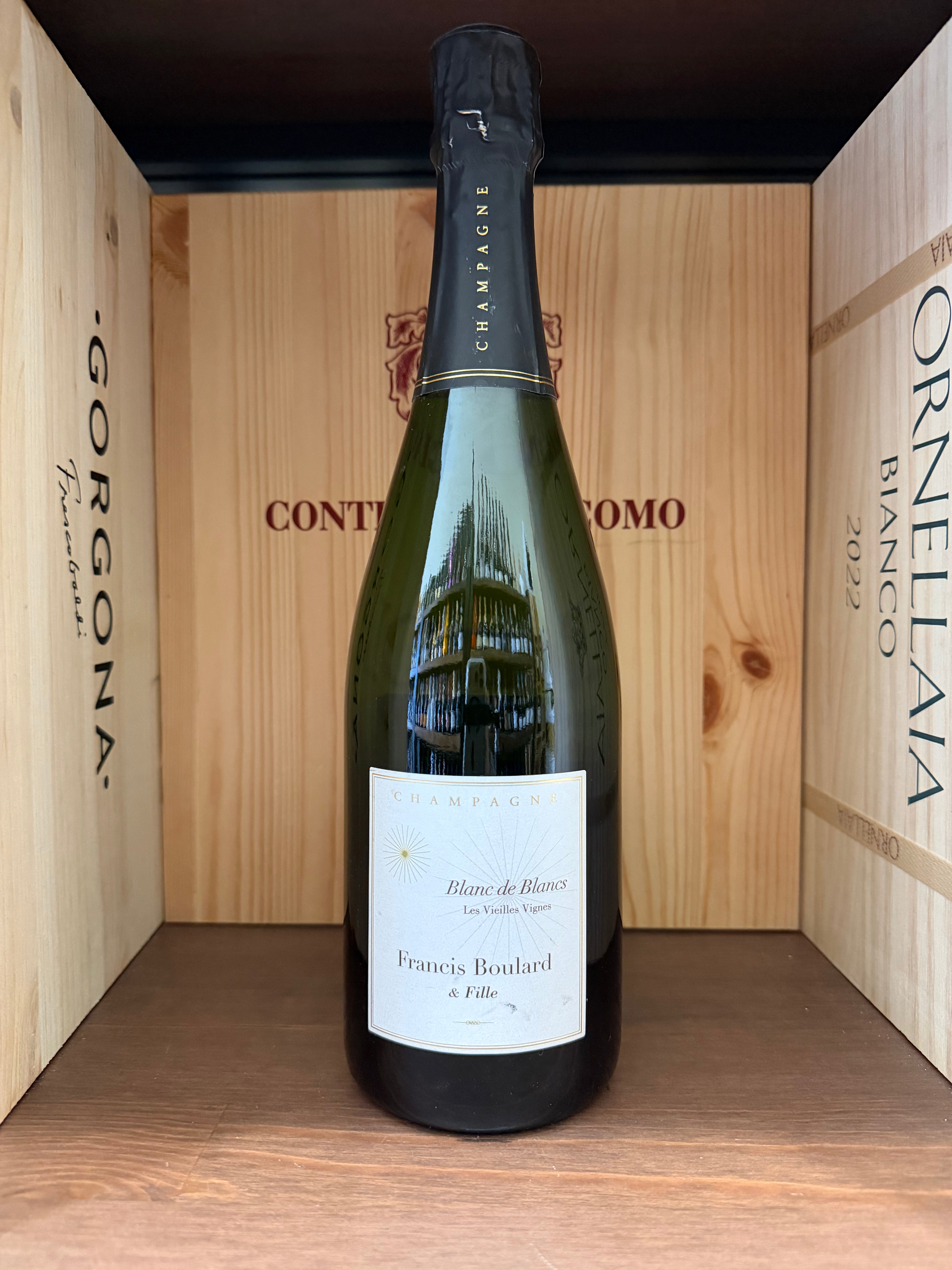 Calice di vino Francois Boulard Blanc de Blancs, bottiglia di Champagne enoteche Toscane su tavolo con bicchiere.