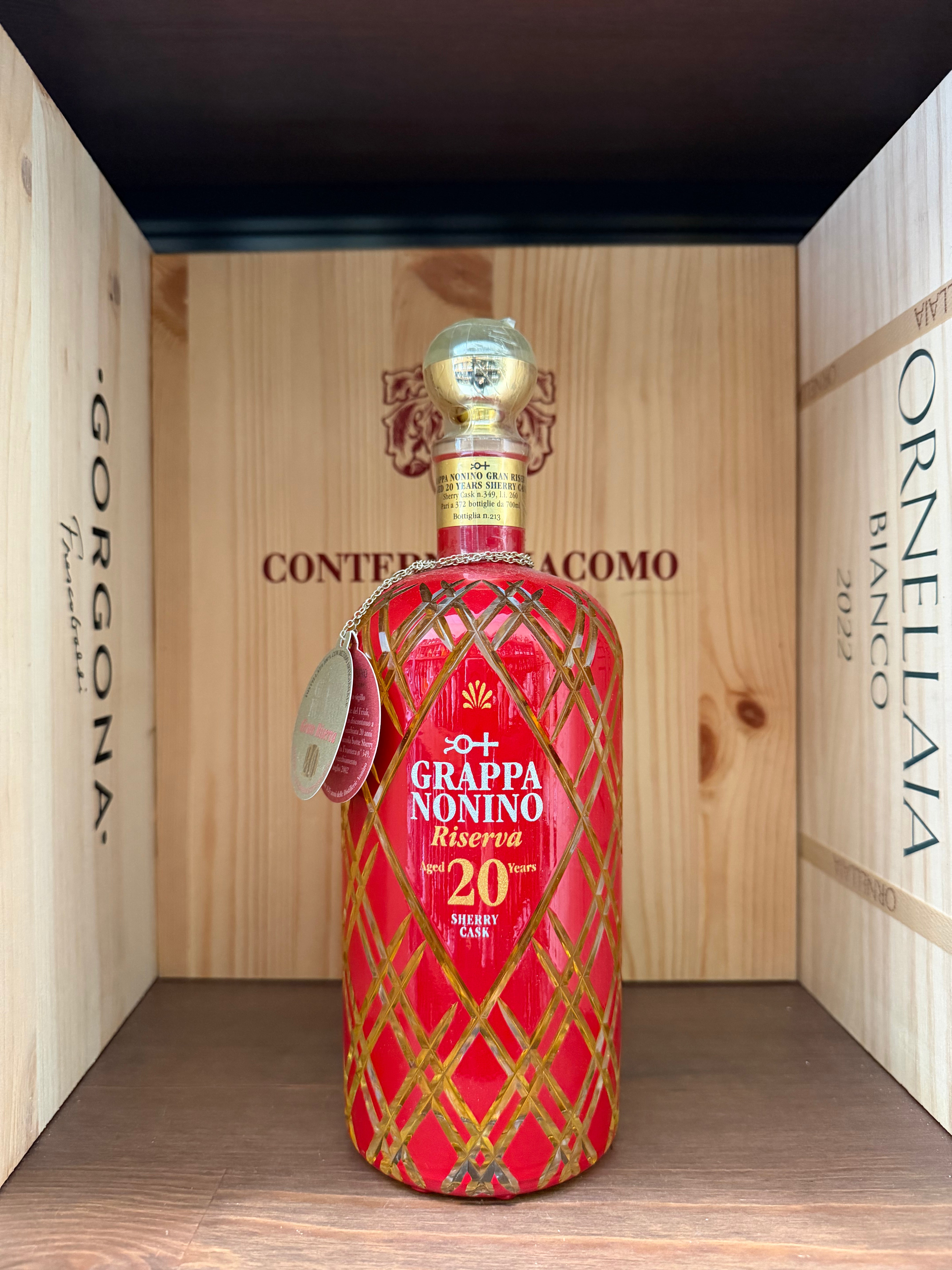 Bottiglia di Grappa Nonino Riserva 20 Anni con etichetta elegante, in un bicchiere elegante, su sfondo neutro.