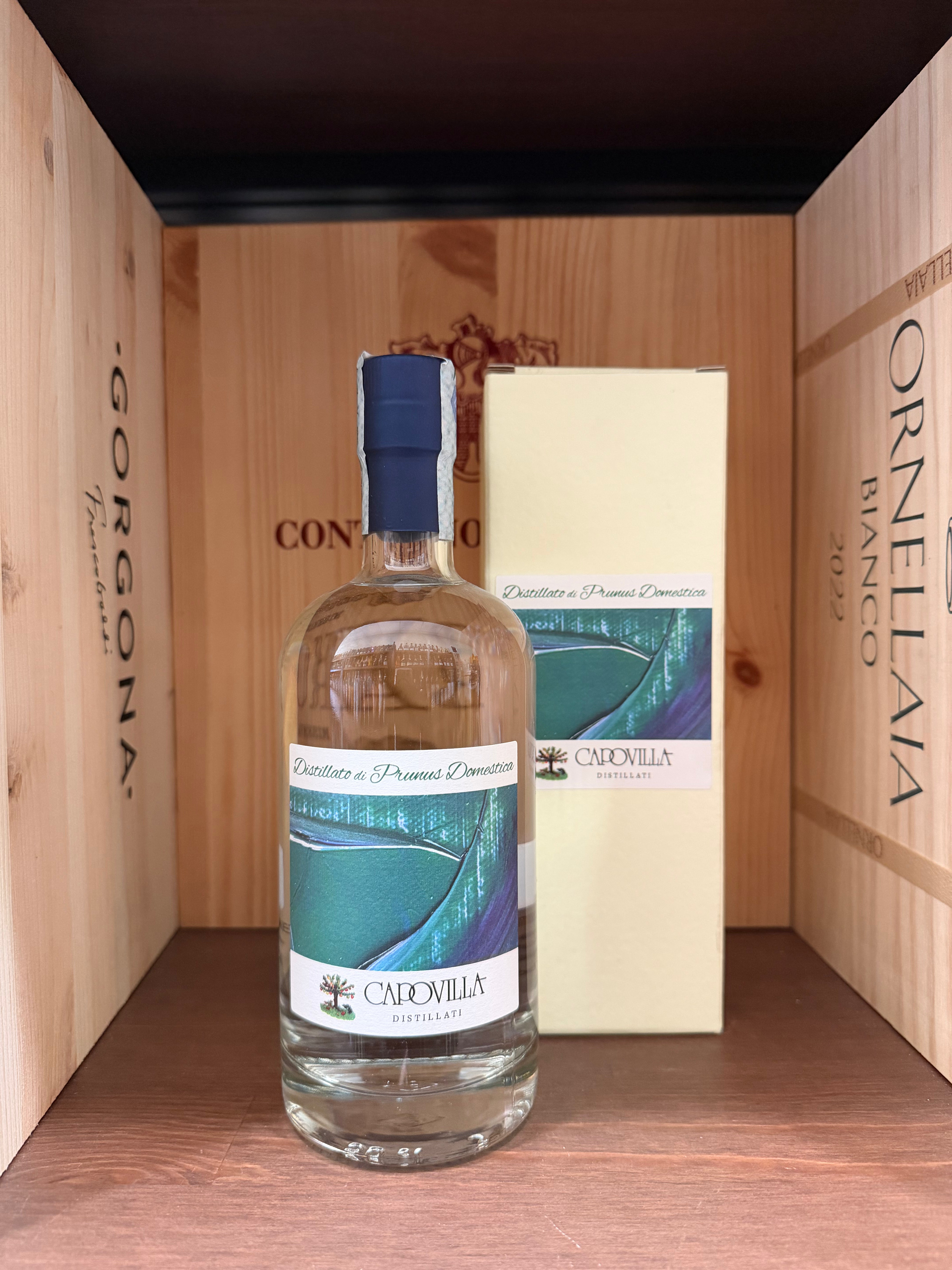 Distillato di Prunus Domestica Capovilla in bottiglia, dettagliata immagine del liquido dorato e del packaging elegante.