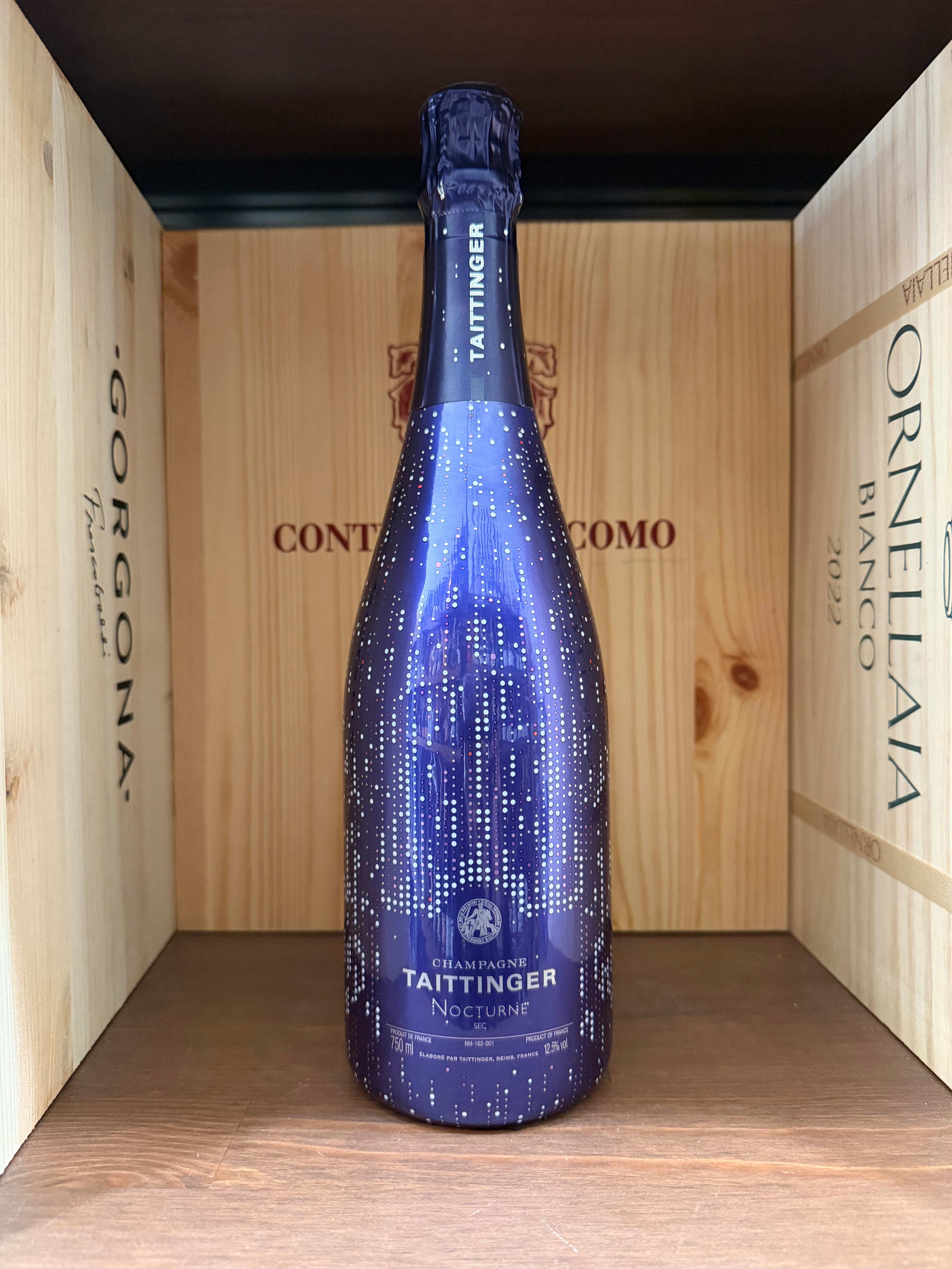 Bottiglia di champagne Taittinger Nocturne Cuvée su una superficie neutra, vista frontale, evidenziando l'etichetta elegante.