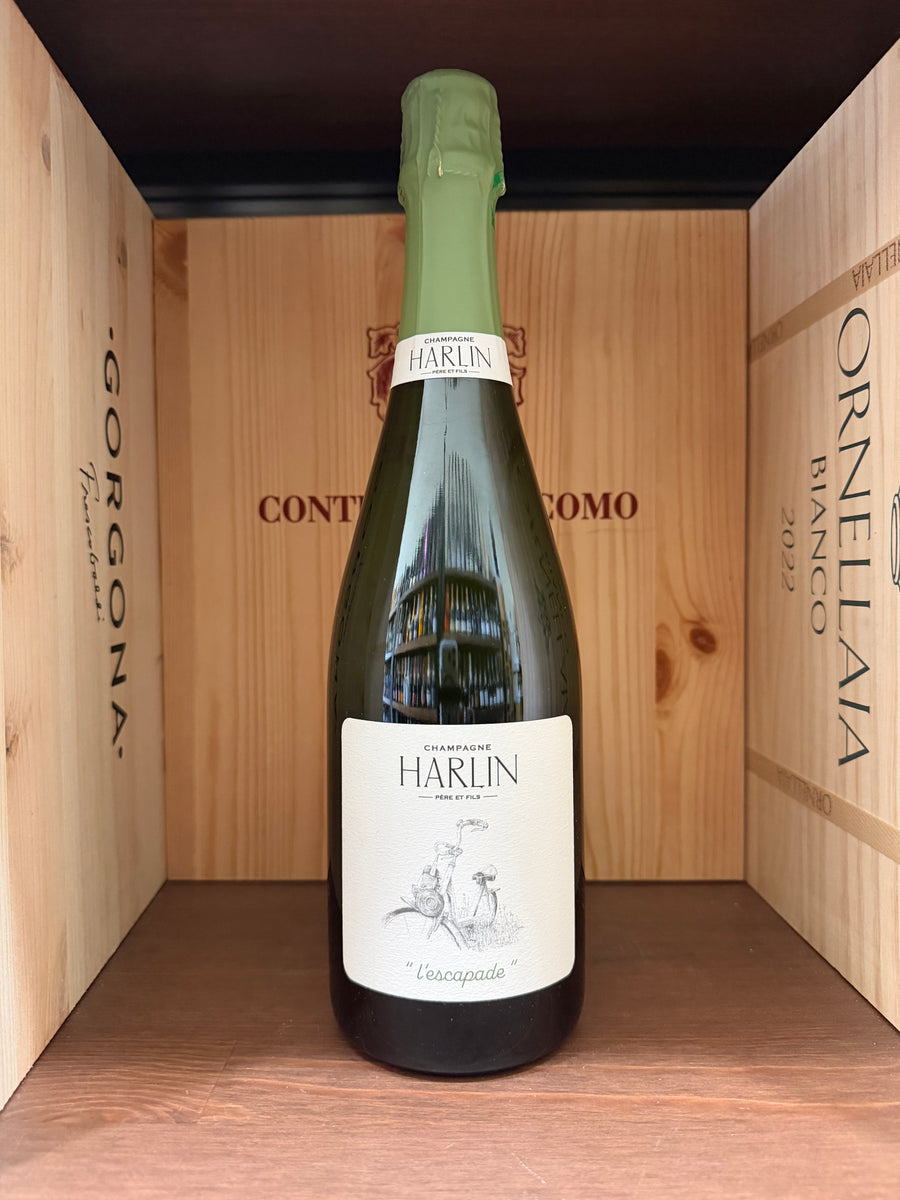 Bottiglia di vino Harlin Lèscapade di Enoteche Toscane, etichetta elegante con dettagli artistici, in una cornice rustica.