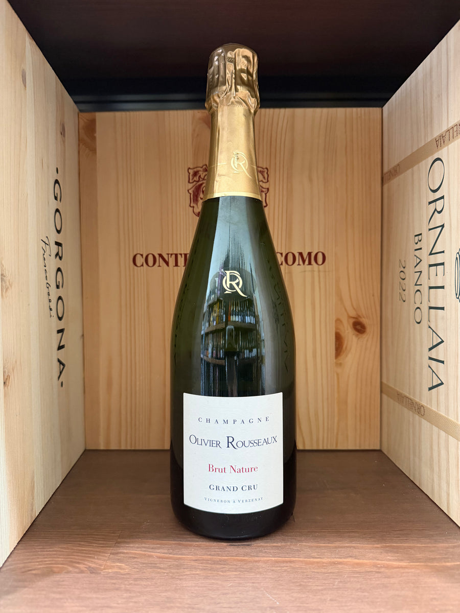Bottiglia di Olivier Rousseaux Gran Cru Brut Natur, vino spumante, con etichetta elegante, in un calice di vino.