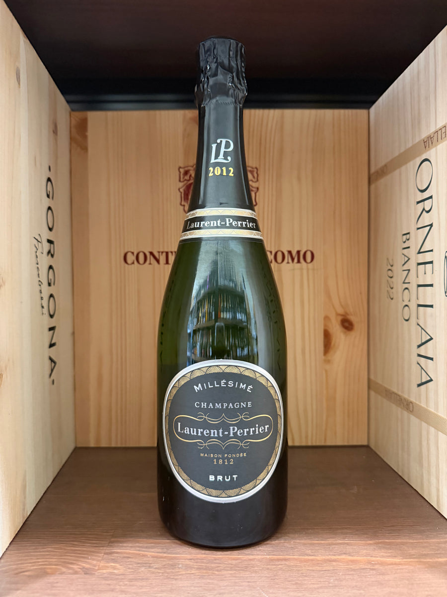 Bottiglia di Champagne Laurent-Perrier Maison Fondée 1812 Brut con etichetta elegante, in un calice di vetro.