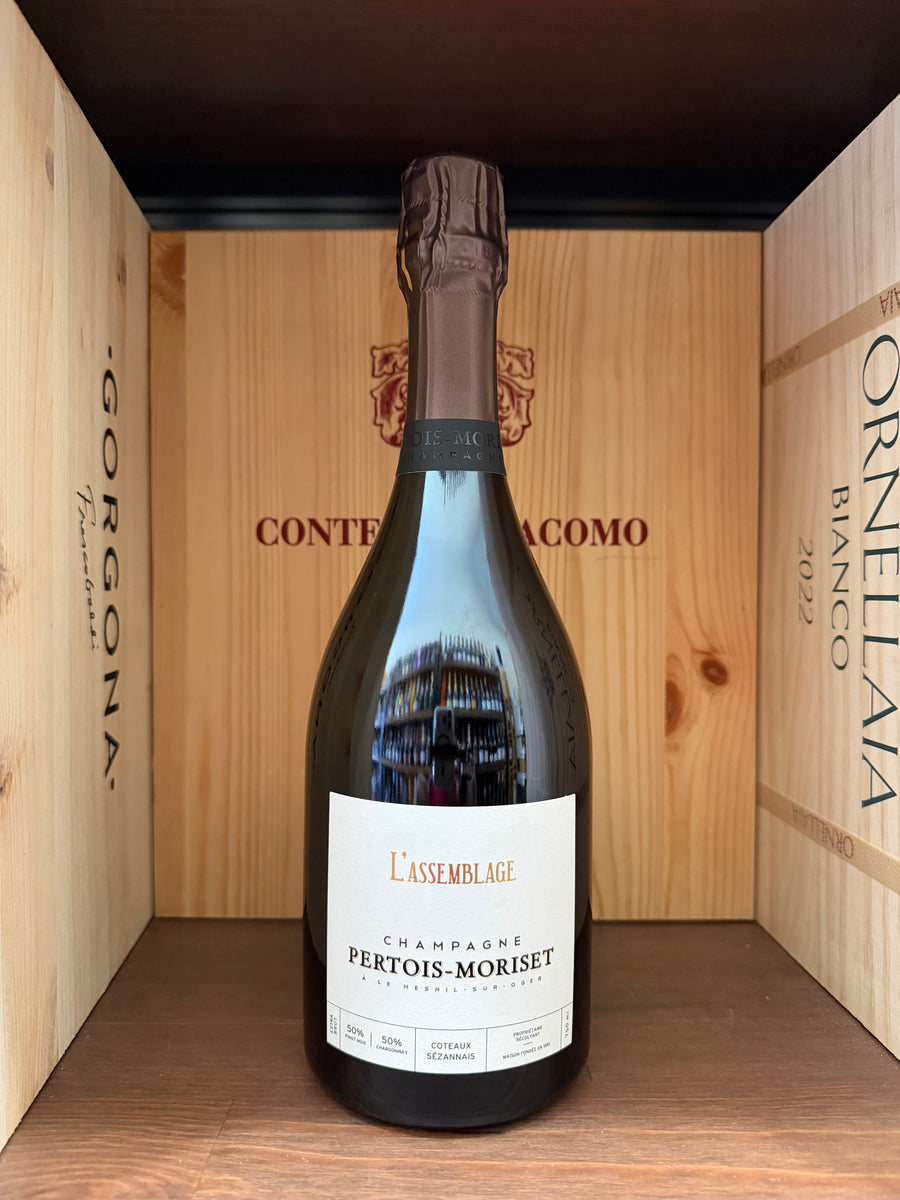 Bottiglia di vino Pertois-Moriset L'Assemblage, etichetta elegante, in un calice di vino rosso.