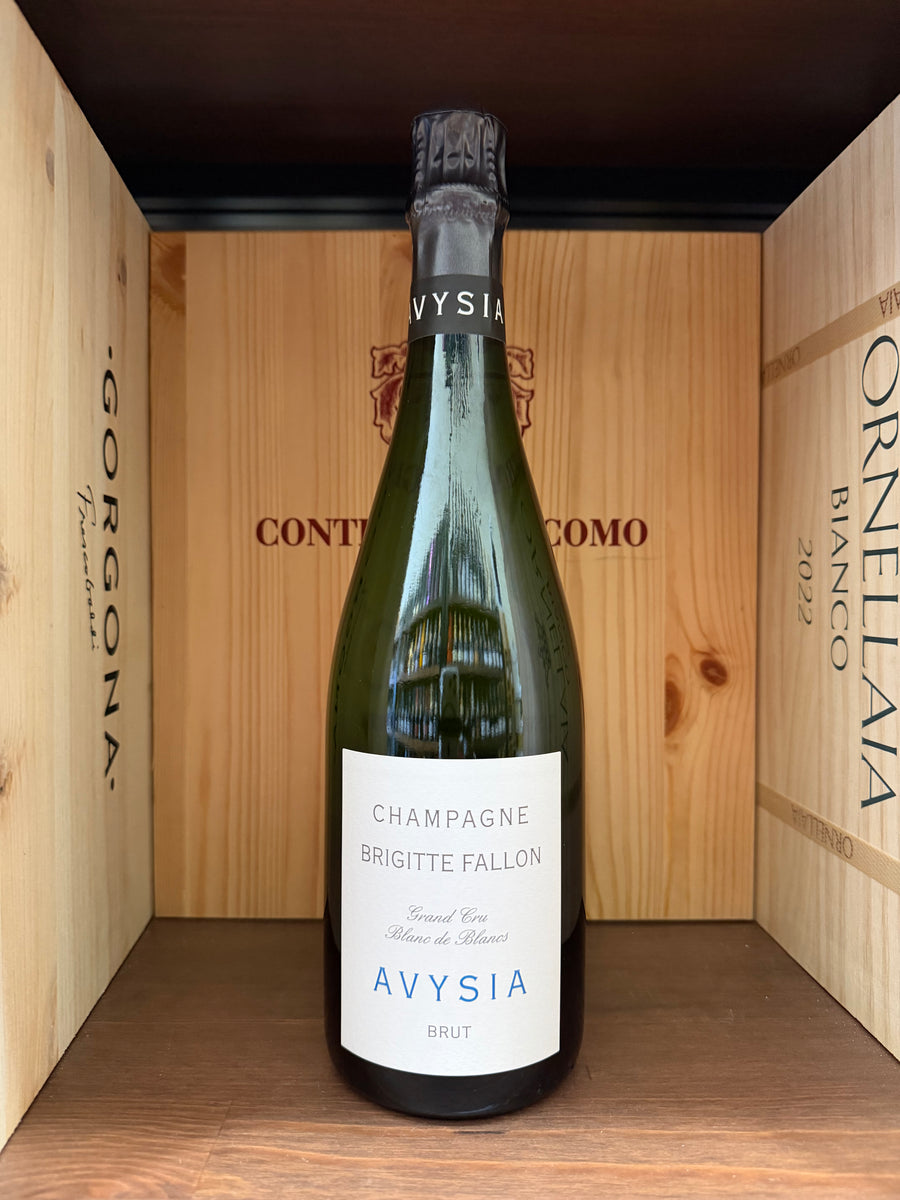 Calice di vino Gran Cru Blanc de Blancs Brigitte Fallon Avysia, bottiglia elegante su sfondo chiaro.